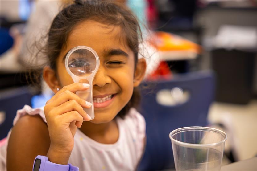 A girl looks through a magnifying glass
